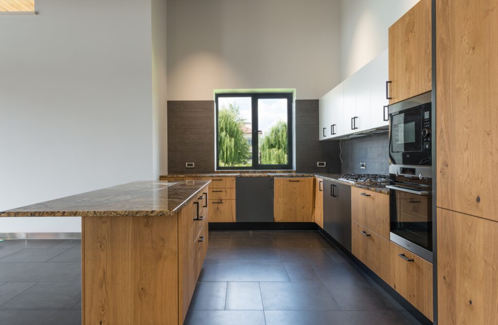 Interior of spacious kitchen with wooden counter located in middle with built in stove appliances and many cabinets